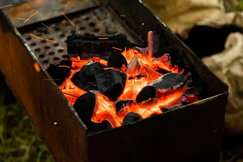 Glowing charcoal emits heat and sparks in a barbecue grill. Ideal for outdoor cooking