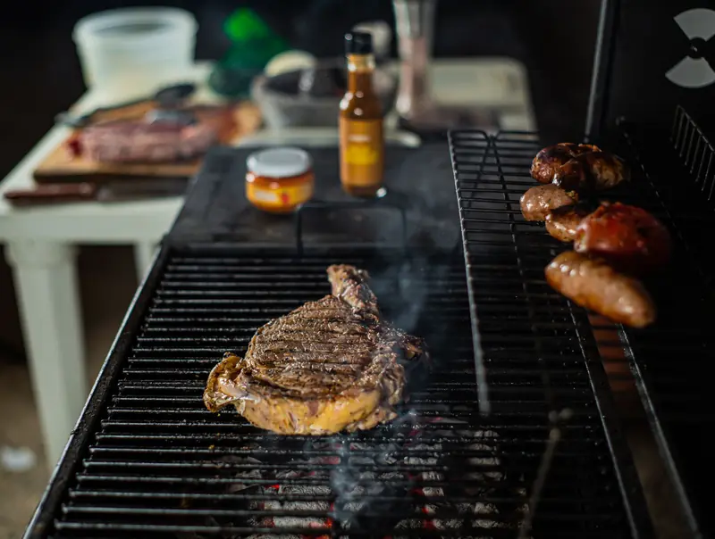 Close-up of steak and sausages grilling outdoors, captured in vibrant detail