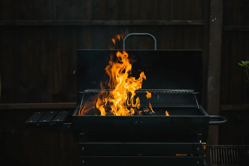A close-up of an outdoor barbecue grill with blazing flames over charcoal, perfect for summer grilling