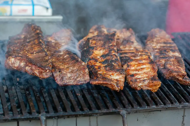 Close-up of delicious grilled ribs smoking on a barbecue grill, perfect for a summer cookout