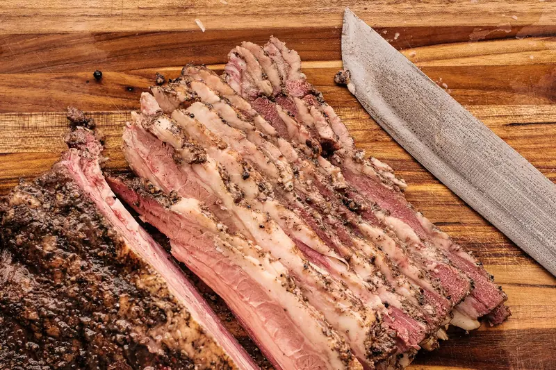 A detailed view of sliced brisket on a wooden cutting board with a knife