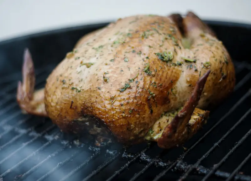 Whole chicken seasoned with herbs, grilled to perfection on a barbecue grill