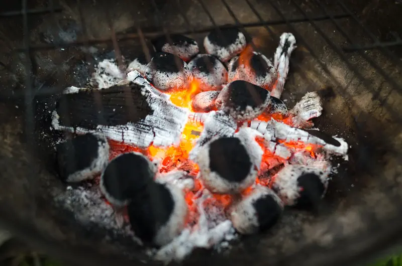 Close-up of glowing charcoal briquettes in a barbecue, ready for grilling