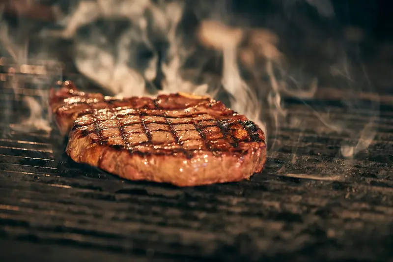 Close-up of a juicy grilled steak with smoke rising, sizzling on a barbecue grill