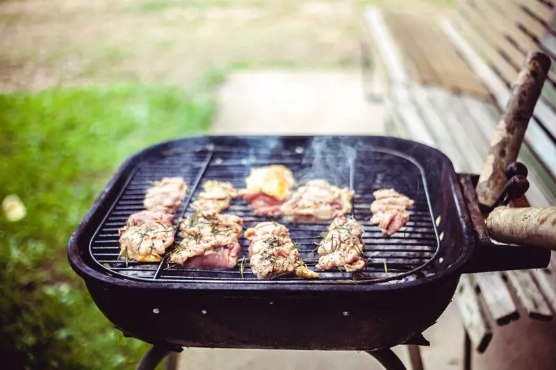 Juicy beef and chicken sizzling on a charcoal grill during a sunny outdoor cookout
